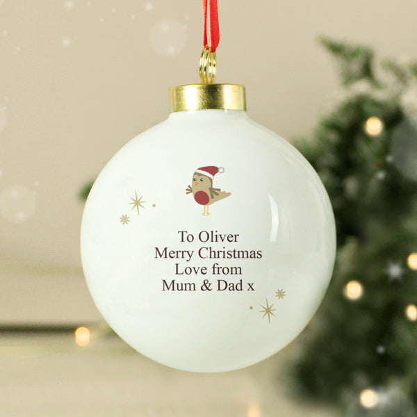Personalized Christmas ornament with a rooster design and text, hanging against a blurred festive background.