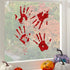 Red bloody handprint decorations on a window with pumpkins in front