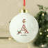 White Christmas ornament with letter 'A' and name 'Amelia', featuring a red checkered pattern and Santa hat design, against a blurred Christmas tree background.